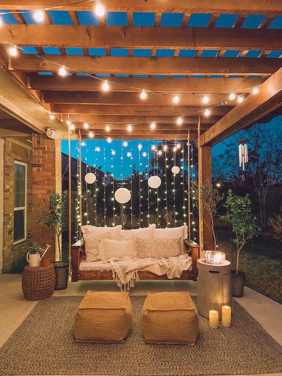 vertical and usual string lights plus paper lamps and candles and a modern fire pit is a stylish idea for a backyard
