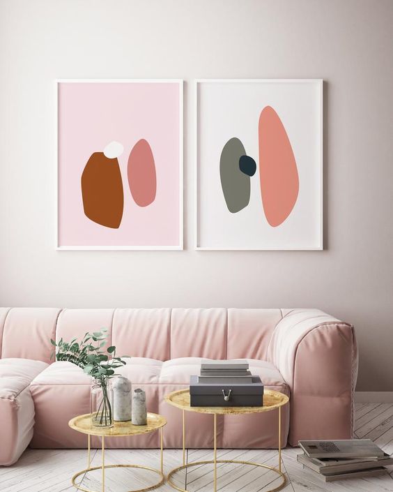 a chic minimalist living room done in neutrals but accented with a light pink sofa, round tables and bold artworks