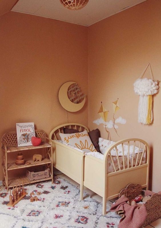 A warm earthy tone kid's room with warm colored walls, stylish furniture, printed textiles and lots of toys