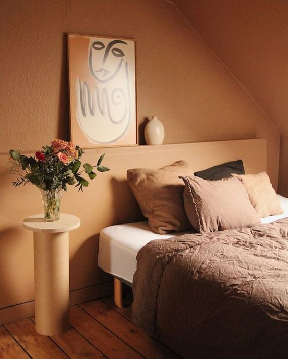 17 a warm earthy tone bedroom with a lovely wall color, comfy furniture and an artwork plus a bit of cool pillows