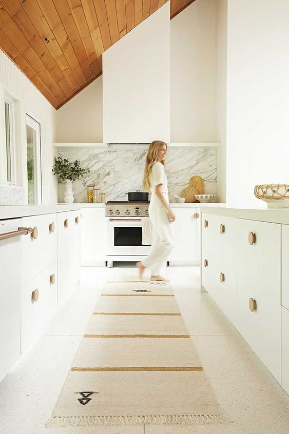 a serene white kitchen with cool cabinetry, wooden knobs and a matching white hood that doesn't differ form them at all