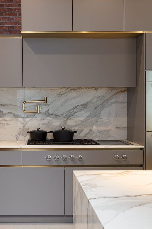 a sleek minimalist grey kitchen with chic cabinetry, gold touches and an integrated hood that looks like a cabinet