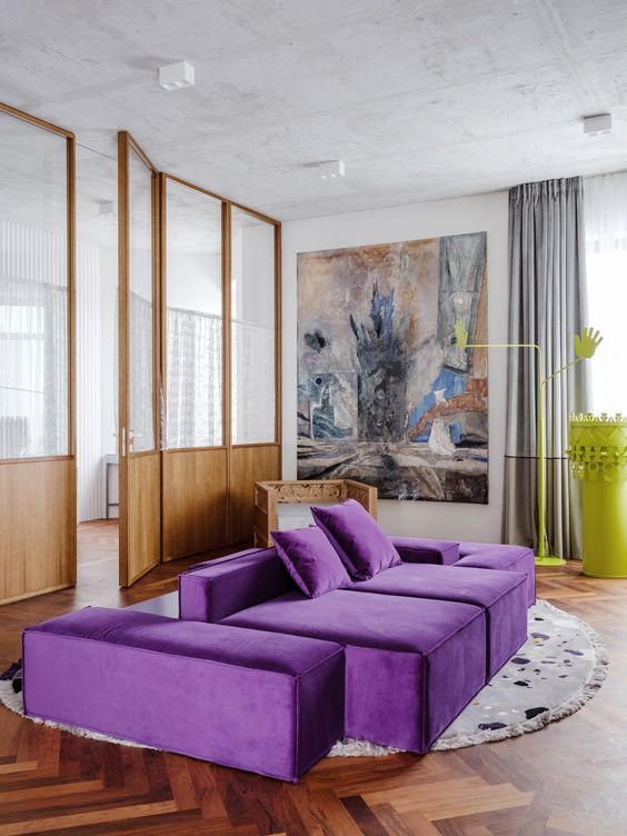 a contemporary living room with a neutral base, a bold purple sofa, a statement artwork, grey curtains and a neon yellow table