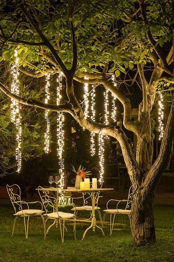 an outdoor dining space with refined metal furniture, candles on the table and hanging lights over the space