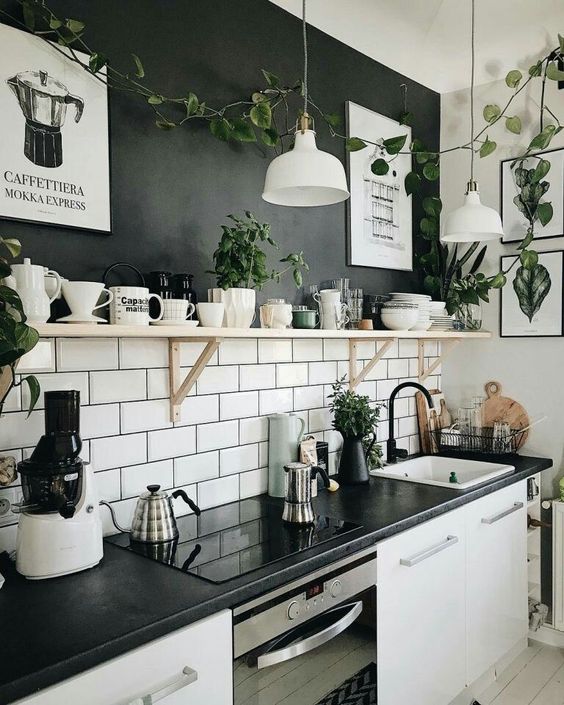 a chic kitchen design in black and white, with a black and white subway tile accent wall, white cabinetry and black countertops