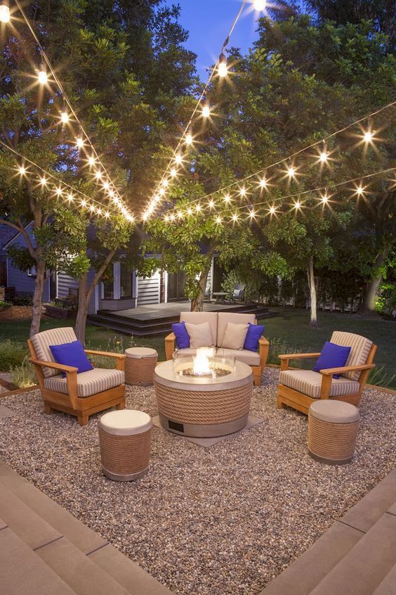 22 a stylish modern outdoor living room with a modern fire pit and string lights over the space is welcoming and chic