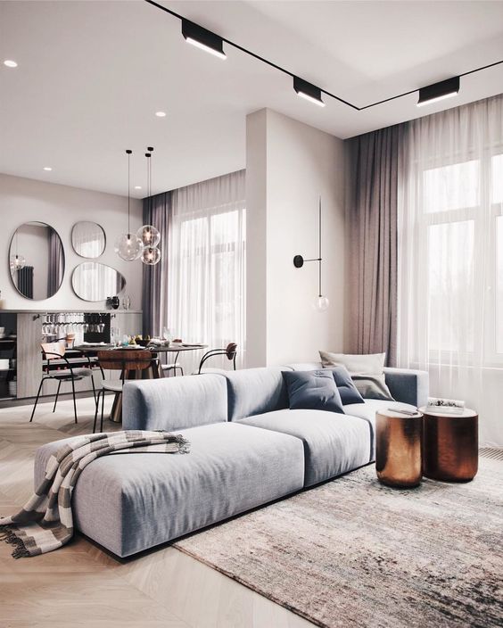 a catchy minimalist interior done in the shades of grey and with a light blue sofa and copper side tables