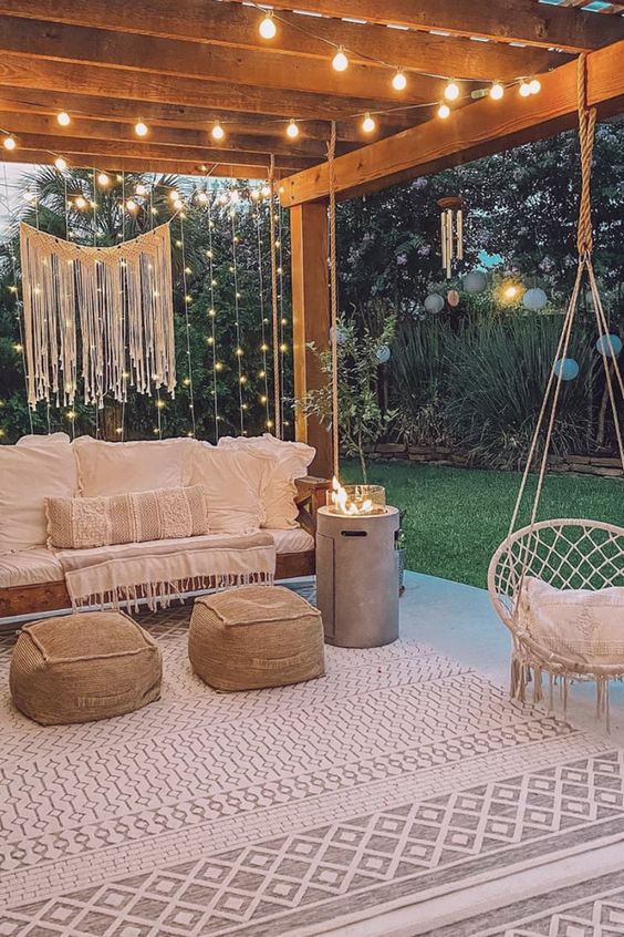 a welcoming backyard patio with boho furniture, neutral textiles, string lights and macrame over the space