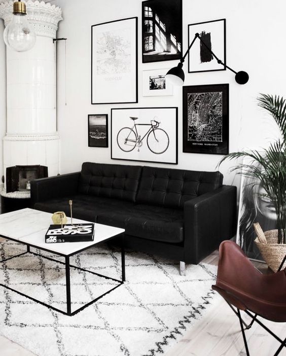 24 a Scandinavian living room with a black leather sofa, a leather chair, a low coffee table and a black and white gallery wall