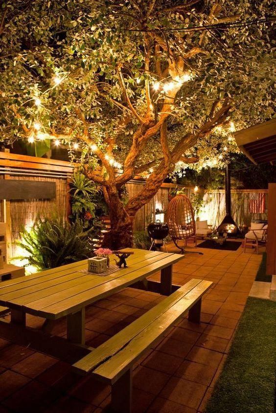 A stylish and cozy backyard with strign lights on the branches and built in lights looks very welcoming