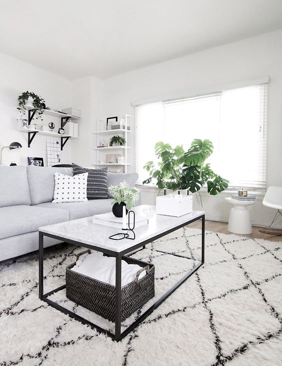 a Scandinavian living room with a grey sofa, black and white furniture, potted plants, a black basket and a printed rug