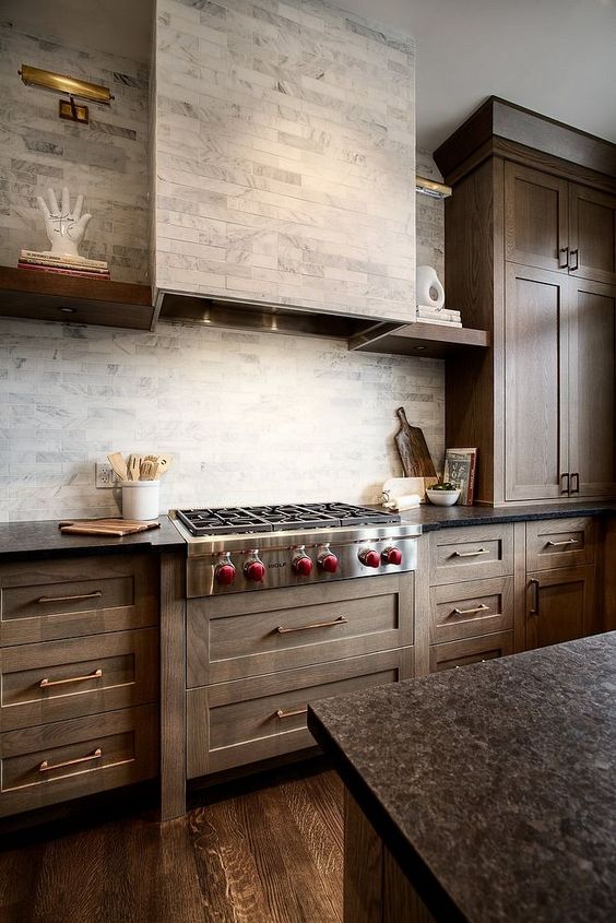 29 a farmhouse kitchen with stained cabinets, a grey marble backsplash and a hodo clad with the same tiles for a seamless look