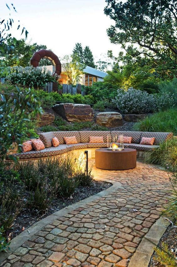 A welcoming backyard with a built in bench, a contemporary fire pit and outdoor lamps for a stylish and cool look