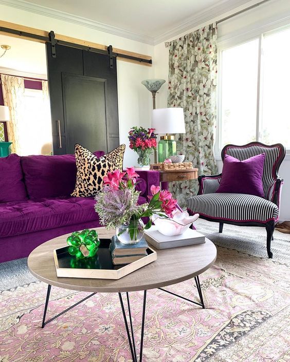 32 a refined modern living room with a barn sliding door, a bold purple sofa, a refined chair, a round table and floral curtains