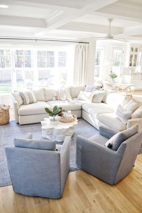 32 a stylish living room with a large white sectional, blue chairs and a rug and some baskets for storage and decor