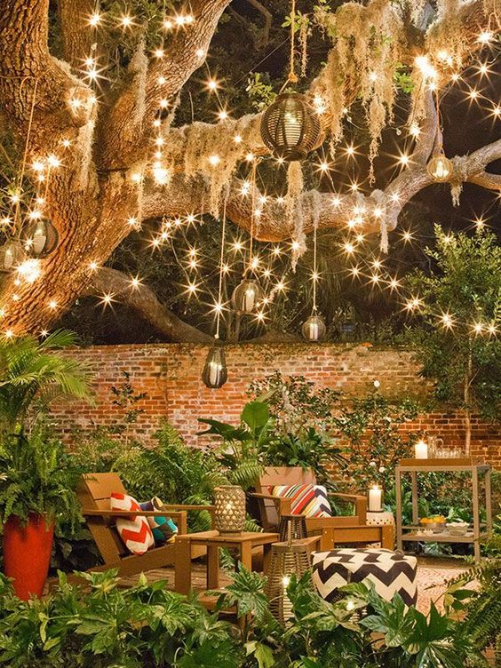 34 a backyard space with lots of string lights, rattan pendant lamps and candle lanterns all over the space is very cool