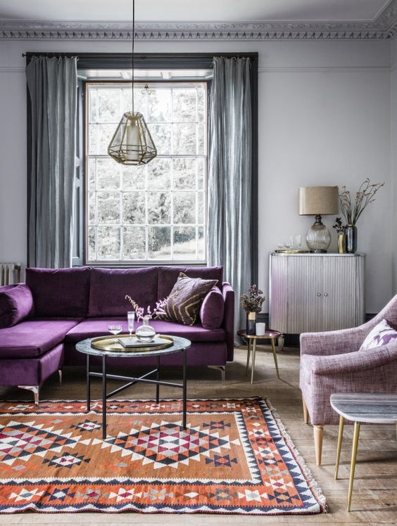 34 a serene living room with light grey walls, grey curtains, a purple sectional, a lilac chair and a printed rug