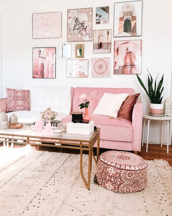 a glam living room with a pink sofa and ottoman, a pink gallery wall, a glass coffee table and a Moroccan rug
