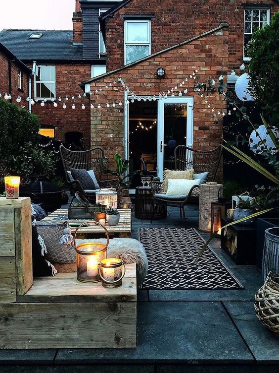 39 a welcoming backyard with pallet and rattan furniture, with printed textiles, candle lanterns and string lights over the space