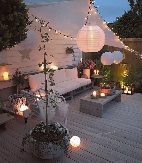 40 a welcoming deck with modern pallet and rattan furniture, candle lanterns, string lights and paper lamps over the space