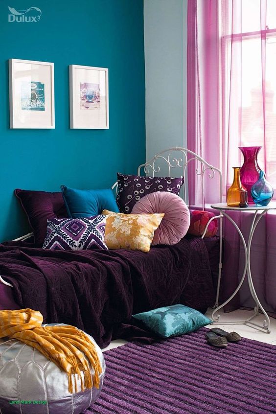 a bold boho nook with a teal wall, a daybed with purple, teal, mauve and yellow textiles, a purple rug and bold vases