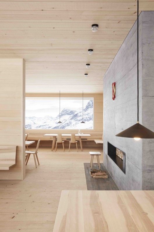 a beautiful chalet space fully clad with blonde wood including blonde wood furniture and a concrete clad fireplace