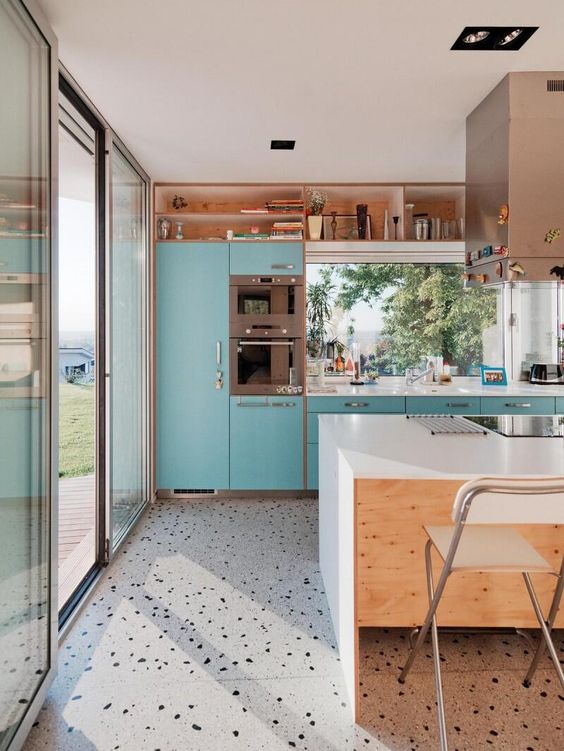 a bright turquoise kitchen with a white kitchen island and a grey terrazzo floor is a playful and cheerful and looks bold