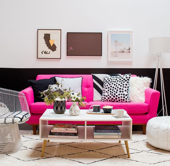 a chic modern lviing room with a color block wall, hot pink sofa, a storage coffee table and a lovely gallery wall