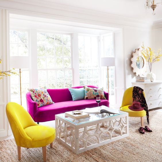 a chic neutral living room in modern farmhouse style, with a hot pink sofa, sunny yellow chairs, a glass table and colorful pillows