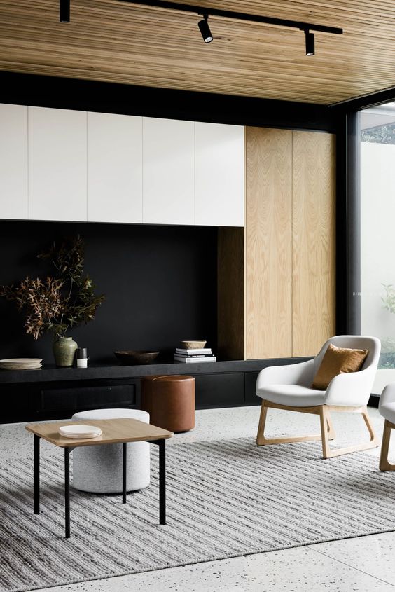 a contemporary living room with a gorgeous storage unit in white, black and blonde wood, with blonde wood furniture and a ceiling