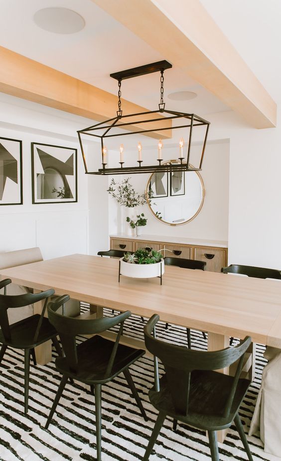 a contrasting dining room with blonde wood beams, a blonde wood table and black chairs plus a gorgeous vintage-inspired black lamp