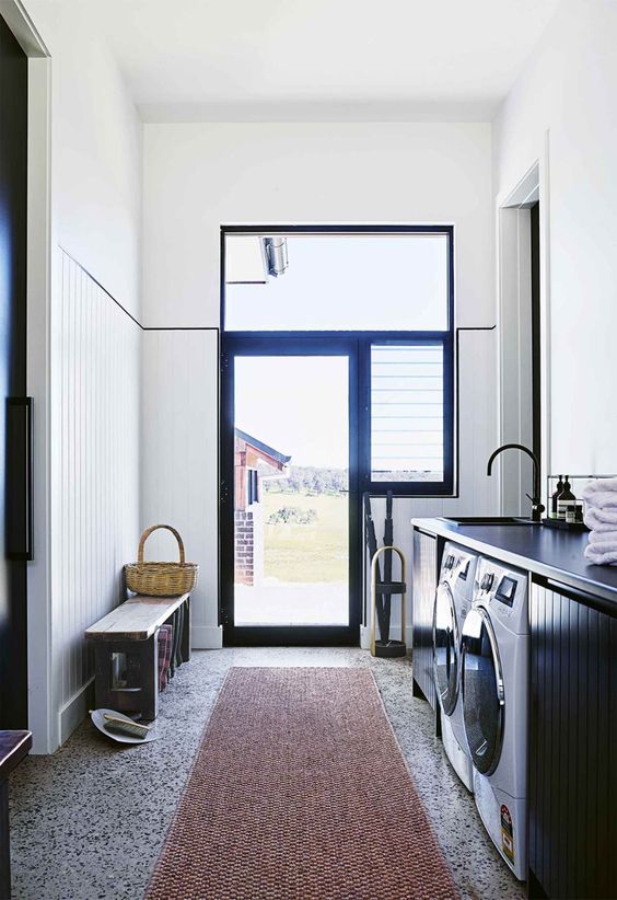 a laundry room done in black and white, with grey terrazzo tiles on the floor that add a cool and fun touch