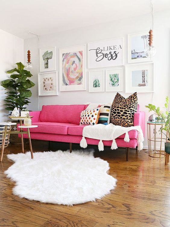 a lovely modern living room done in neutrals, witha pink sofa, an airy gallery wall, white textiles, potted plants and some tables