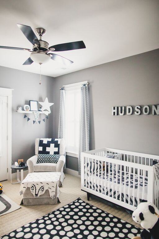 a modern monochromatic nursery with grey walls, white furniture, printed textiles, a name on the wall and pretty decor