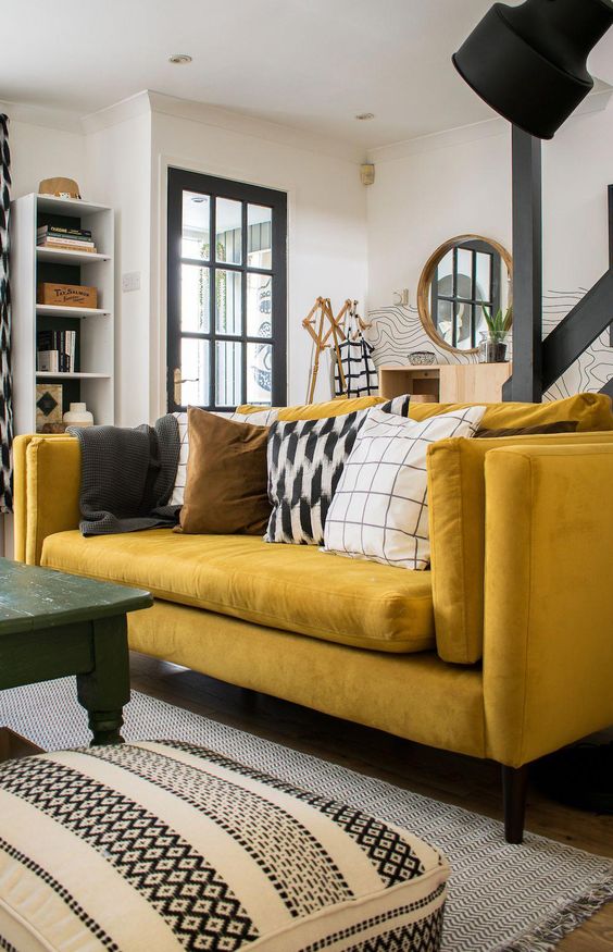 a monochromatic living room with graphic prints, a bold yellow sofa, a green table and a cool shelving unit