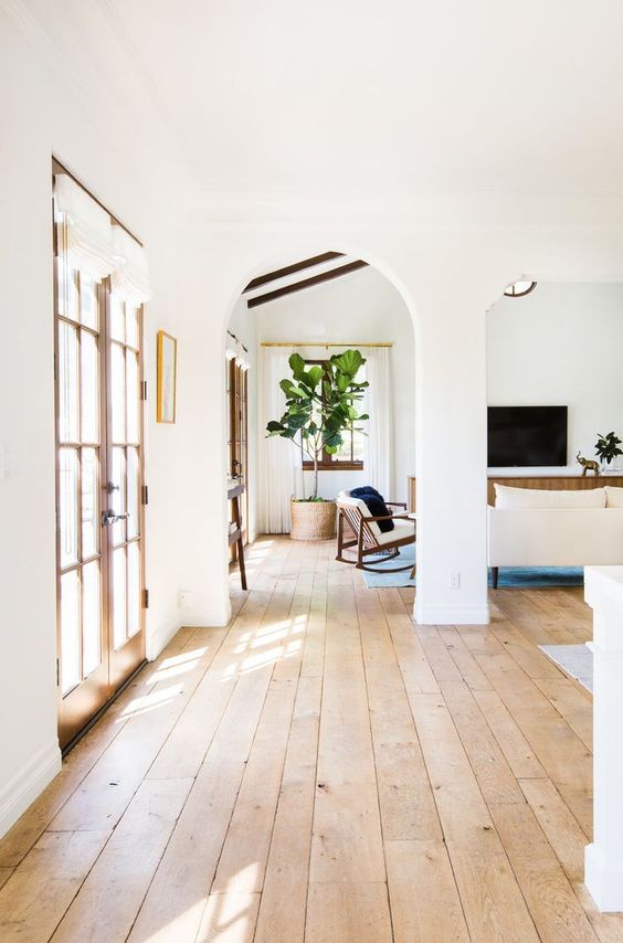 a neutral farmhouse entryway with blonde wood floors, French doors and neutral furniture is chic and cool