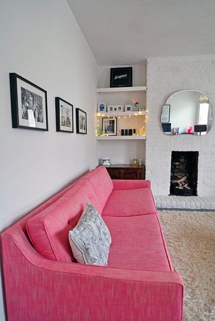 a neutral living room with a non-working fireplace, built-in shelves, a pink sofa for a touch of bold color and a grid gallery wall