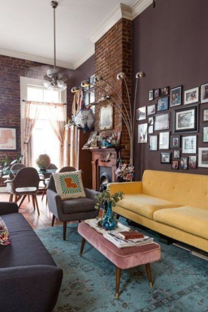 a refined mid-century modern living room with brown walls, a yellow sofa, a grey one and pretty furniture, a gallery wall