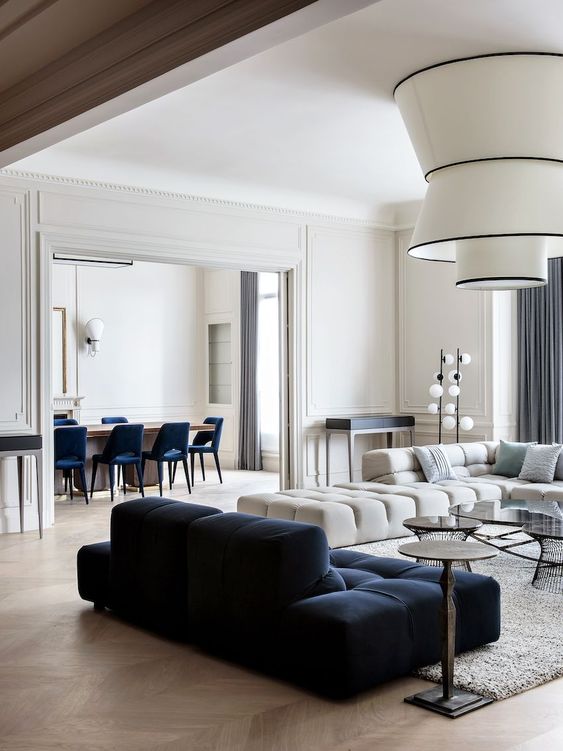a refined modern living room with a creamy and navy low sofa, statement lamps and small round coffee tables