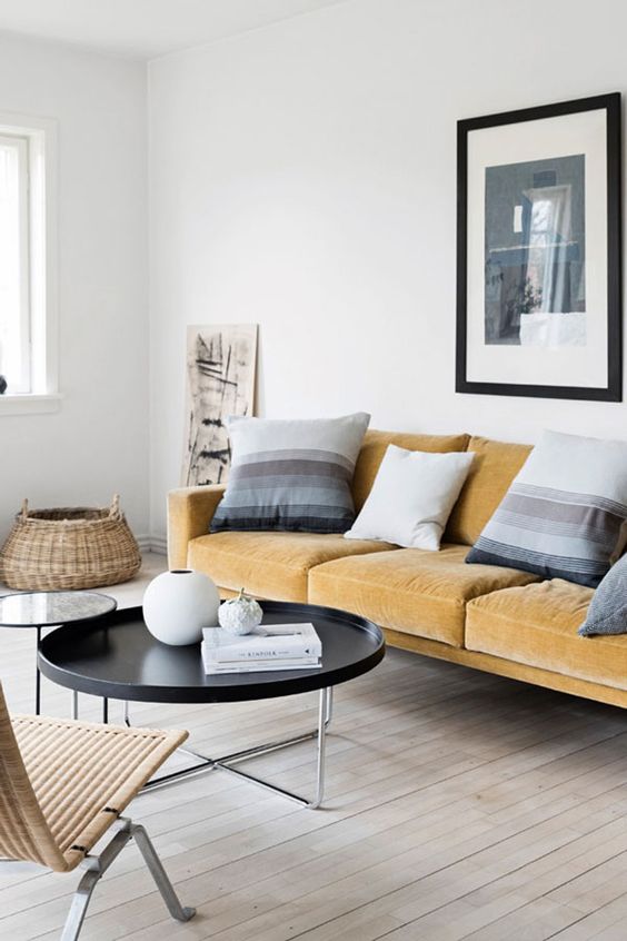 a serene Scandinavian living room with a light yellow sofa, striped pillows, round tables and a rattan lounger is wow