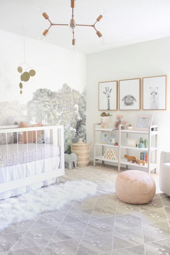 a serene neutral nursery with a forest wall mural, a large crib, a storage unit, a gallery wall with art and some layered rugs