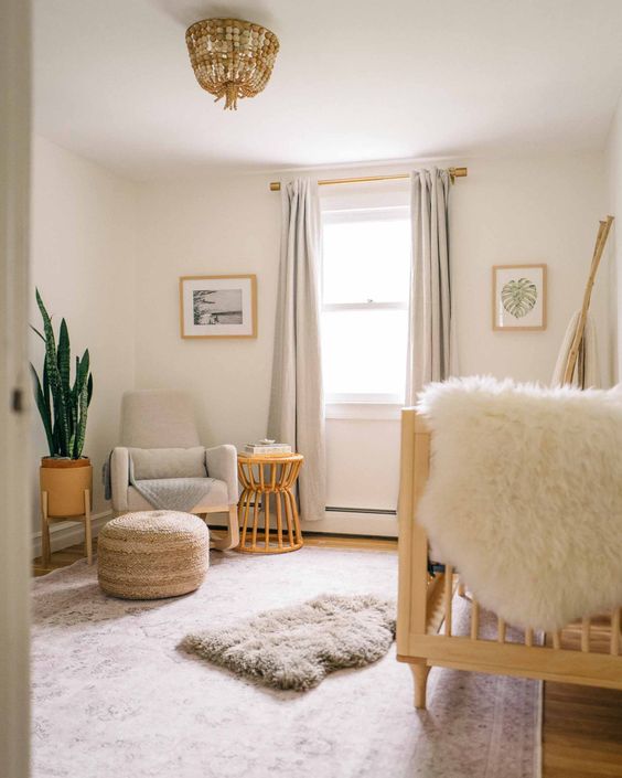 a warm and welcoming neutral nursery with a large wooden crib, a neutral chair, a stool or a side table, a potted plant and a wooden bead  chandelier