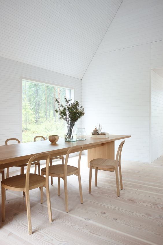 an airy white dining space with a view and a blonde wood dining set with chairs is a very welcoming and clean space