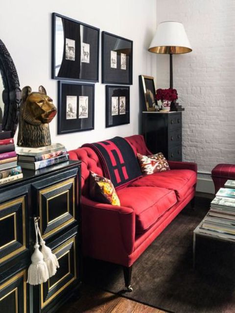 an elegant monochromatic space spruced up with a bold red sofa and an ottoman, made more refined with gold touches
