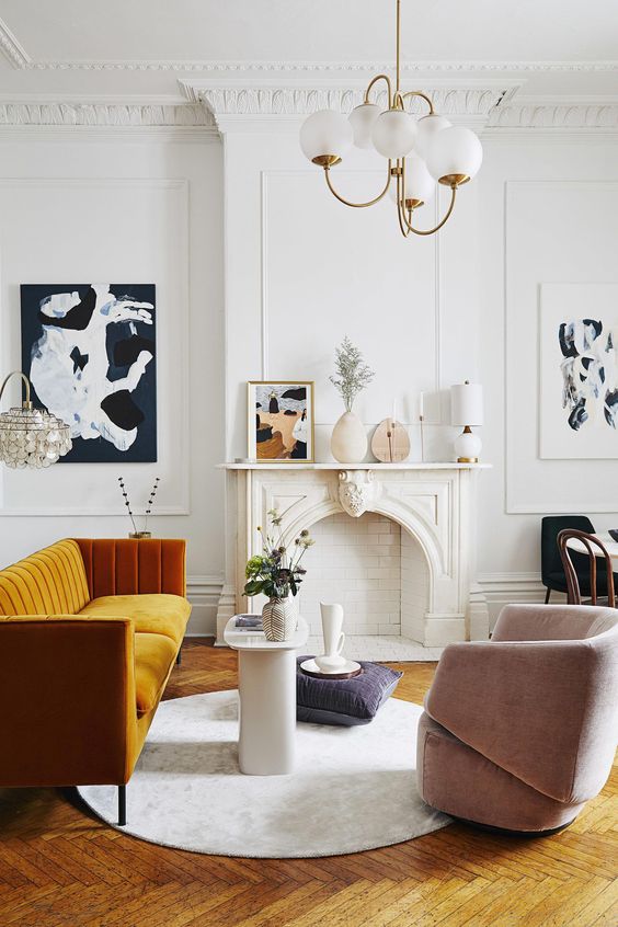 an exquisite Parisian living room with a non-working fireplace, a honey yellow sofa, a blush chair, a retro chandelier and lovely art