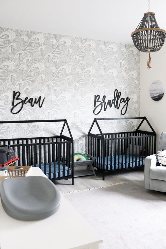 a catchy twin nursery with black cribs, an accent wall, a wodoen bead chandelier and a cool changing table is lovely