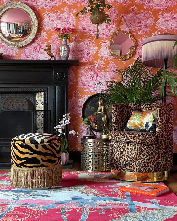 a colorful living room with pink and red wallpaper, a red and blue rug, a fireplace, a leopard print chair and a zebra ottoman