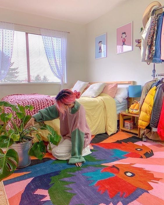 a colorful maximalist bedroom with a bold rug, a bright gallery wall, pastel bedding and colorful curtains plus a potted plant