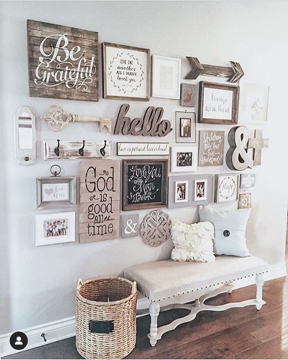 a cozy rustic gallery wall including a wooden arrow, a key, a calligraphy piece, wooden signs and some photos in stained wooden frames