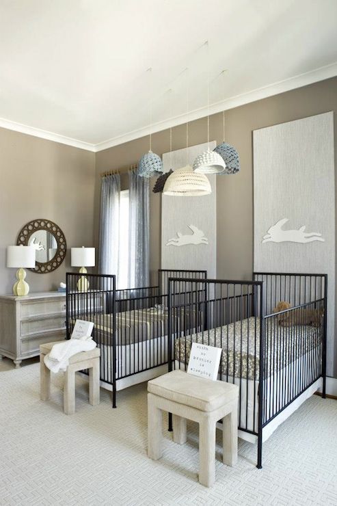 a creative twin nursery with grey walls, black metal cribs, grey stools, crochet pendant lamps and a grey dresser